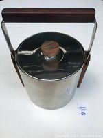 Top view of the ice bucket showing teak handle and teak knob on lid with stainless steel body.