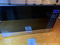 Front view of Panasonic microwave showing stainless steel body and black glass door, placed on wooden surface.