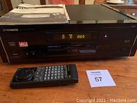 Front view of the Pioneer DV-09 Elite DVD player including the front panel with digital display and buttons, remote control and user manual placed on top.