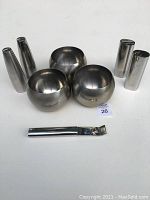 Full view of three round stainless steel bowls, two sets of salt and pepper shakers, and a bottle opener on white background