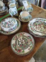Complete set of Indian Tree china on wooden table, showing plates, cups, saucers, pitcher, and covered dish with floral and butterfly designs.