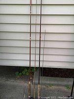 Side view of two sets of JC Higgins fly fishing poles with cork handles in used condition