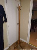 Full view of the tall solid wood hall tree standing in a corner, showing the overall structure and base.