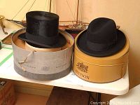 Two black hats displayed in Stetson round hat boxes