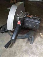 Side angle showing black handle, motor housing, and blade guard of the Turex Model 46 mitre saw on a concrete floor.