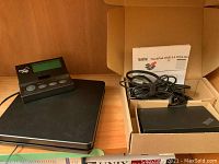 Smart Weigh black digital scale with attached remote LCD display and buttons, Lenovo ThinkPad USB 3.0 Ultra Docking Station in an open box with cables and adapter.