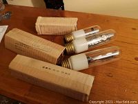 Three tube-style bulbs displayed on wooden surface with original cardboard boxes