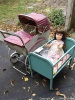 Gendron pram, aqua doll bed with doll seated and blankets visible, driveway background