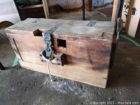 Photo of closed vintage wooden tool box with visible cast metal hasp latch and wood construction.