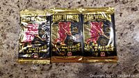 Three unopened black and gold 1996 Pinnacle Game Winner hockey card packs with McDonald's branding shown on a countertop.