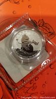Photo of the silver coin featuring snowman design in a clear protective case.
