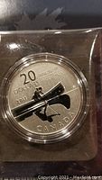 Close-up photo of the 2011 Canadian $20 silver coin featuring a person paddling a birch-bark canoe with inscriptions of denomination, year, silver purity, and Canada.