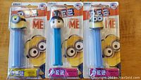 Full view of set of three Despicable Me PEZ dispensers in original packaging, two Minions and one human character.