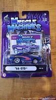 Front view of the unopened Muscle Machines 1:64 scale model showing packaging and car details.