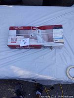Photo of boxed Price Pfister faucet on white cloth surface with boxed packaging showing faucet image and branding.