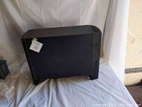 Side view of large black Bose subwoofer showing flat casing with tag attached.