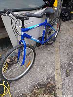 Front-right angled view of the blue Supercycle bike showing frame, handlebars, and front wheel.