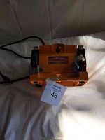 Front view of orange Mastercraft 5-inch bench grinder with power cord attached, showing label and electrical plug.