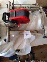 Photo of Minoura stationary bike conversion kit on white cloth background showing the frame, resistance unit, and adjustment knob.