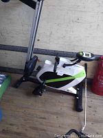 Side view of stationary rowing machine featuring digital display, foot pedals with straps, and a stable frame.