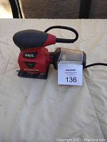 Front and side views of the red and black Skil fine orbital sander with dust canister attached