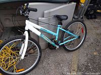 Front side view of the white to light blue Triumph bicycle showing tires, frame, and handlebar.