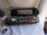 Two camping tents in their original packaging, one in a green bag showing 4-person occupancy, the other in a black bag for 2-person occupancy.