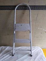 Photo of white two-step ladder front view showing two steps and curved handle