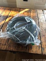 Top view of one small black wheel wrapped in plastic, showing tire tread and hub center.