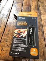 Image showing front of the original boxed CTEK battery charger and maintainer resting on wooden floor.