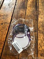 Ultralight guitar capo fully packaged on a wooden surface showing its small compact shape and purple accented packaging.