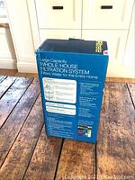 Photo of the blue boxed 3M Filtrete whole house filtration system showing detailed product information and branding.