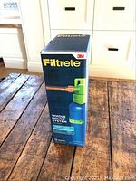 Front view of unopened Filtrete water filtration system box on wooden surface.