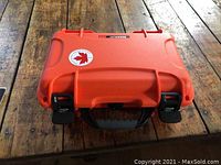 Closed view of the Nanuk 909 orange carrying case from top showing latches, handle, and brand label