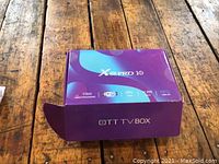 Closed purple box with X88 Pro 10 and OTT TV Box branding on top, placed on wooden table.