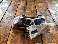 Photo showing Smith brand white frame sunglasses with dark lenses atop Smith branded box and beige cloth pouch on a wooden surface.
