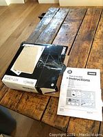 Photo of Thule XT Kit 3028 box sealed with packaging tape on wooden table, showing label KIT-3028 and partial view of contents packaging.