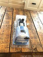 Brand new TotalPond waterfall pump in original plastic packaging shown standing upright on rustic wooden surface.
