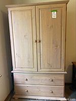 Front view of light wood armoire with two doors above and lower drawer below