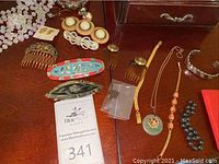 Overview of assorted jewelry and hair accessories on a wooden surface including necklace, bracelet, black beads, and decorative hair combs/barrettes.