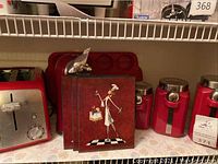 View of red metal canisters with lids, kitchen decor panels showing chef designs on a checkerboard pattern.