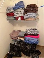 Overview showing top and bottom shelves with folded linens and blankets in multiple colors and materials