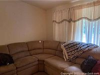 Corner view of L-shaped sectional sofa against wall with throw blanket and pillows
