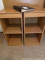 Two small wooden shelving units side by side showing their front with two open compartments each.