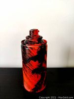 Rear view displaying the predominantly red with black strokes on the sculpture's surface and the nozzle top.
