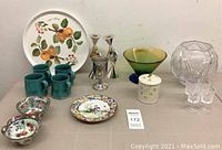 Photo showing assortment of dishes and decor including turquoise mugs, silver candlesticks and kiddush cup, colorful plates, art glass bowl, and Portmeirion platter.