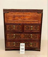 Front view of the carved wooden chest showcasing 5 drawers with brass handles and intricate carvings on drawer fronts and edges.