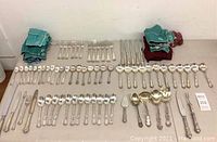 Full spread of flatware arranged on table showing forks, spoons, knives and storage bags