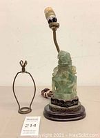 Full view of lamp with removed harp showing carved green quartz body, lamp socket, wooden and metal base