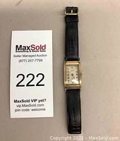 Watch laid flat next to MaxSold lot card 222